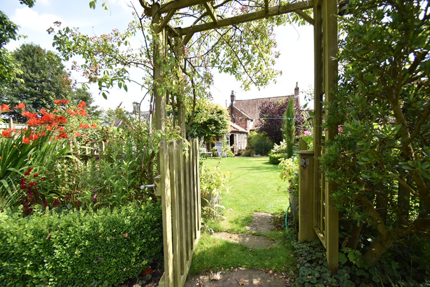 View of the house through a garden gate covered in foliage