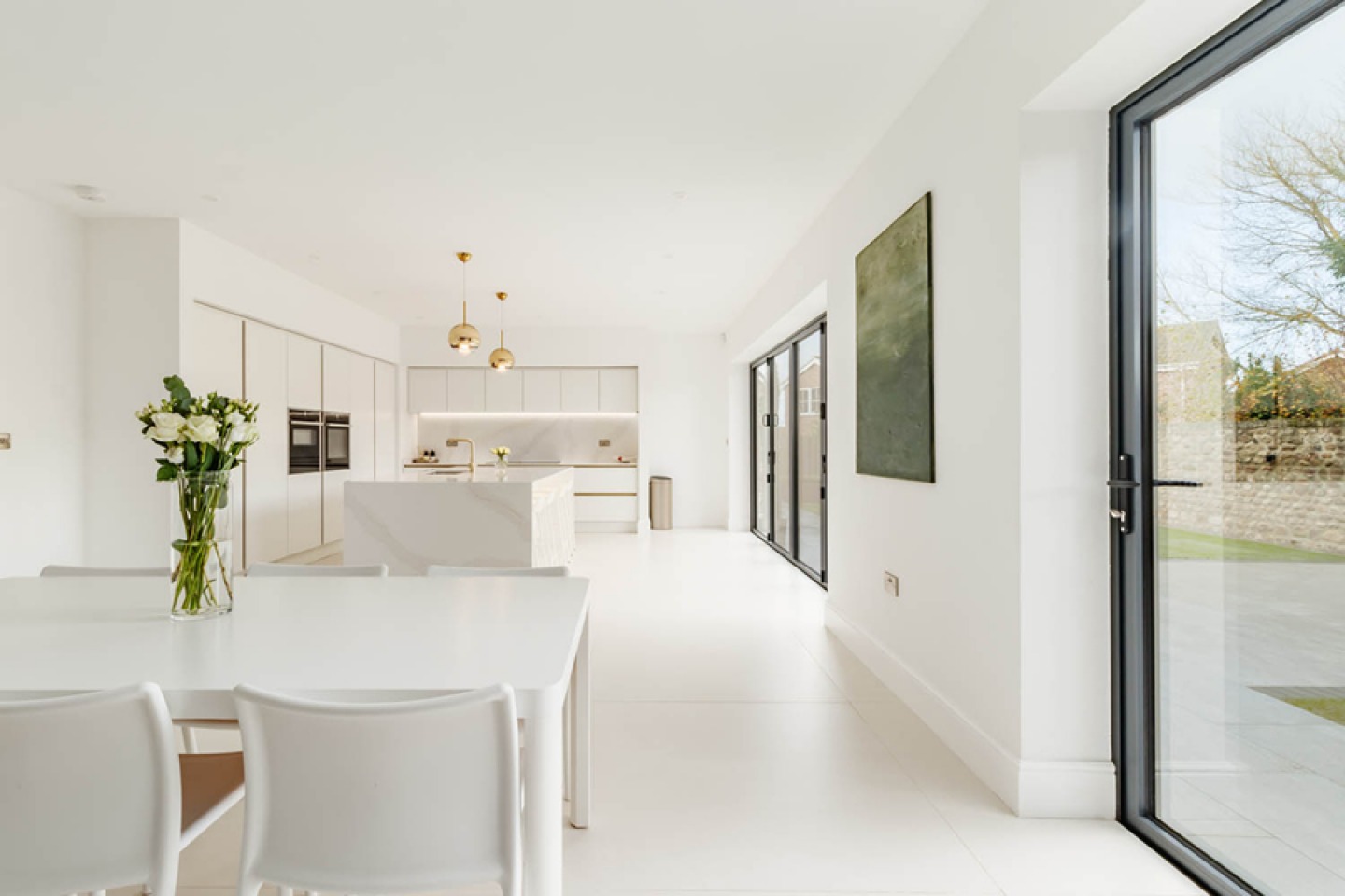 All white, high gloss kitchen diner with large bifold door