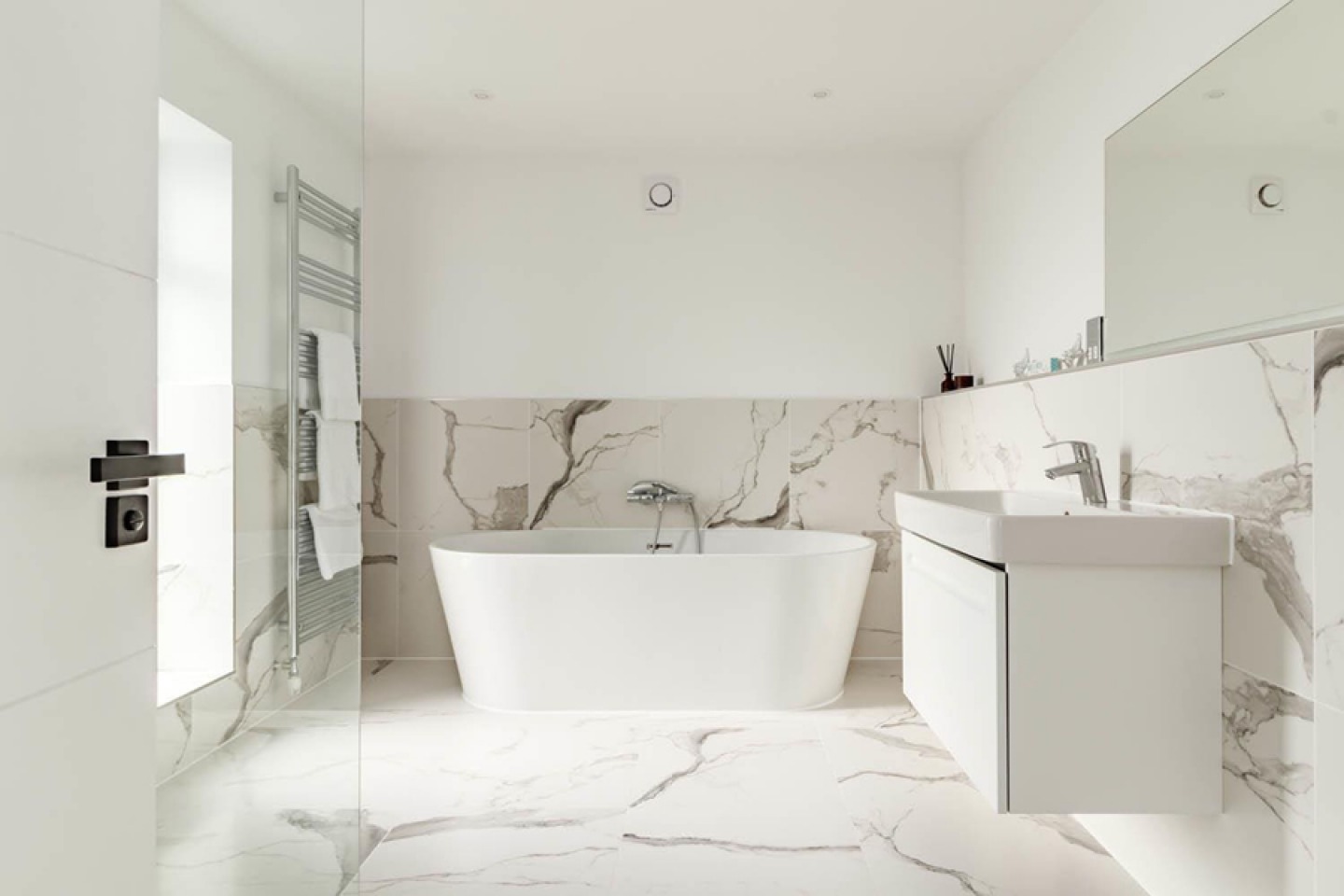 White and grey marble effect tiled floor and walls with free standing bath and floating sink unit