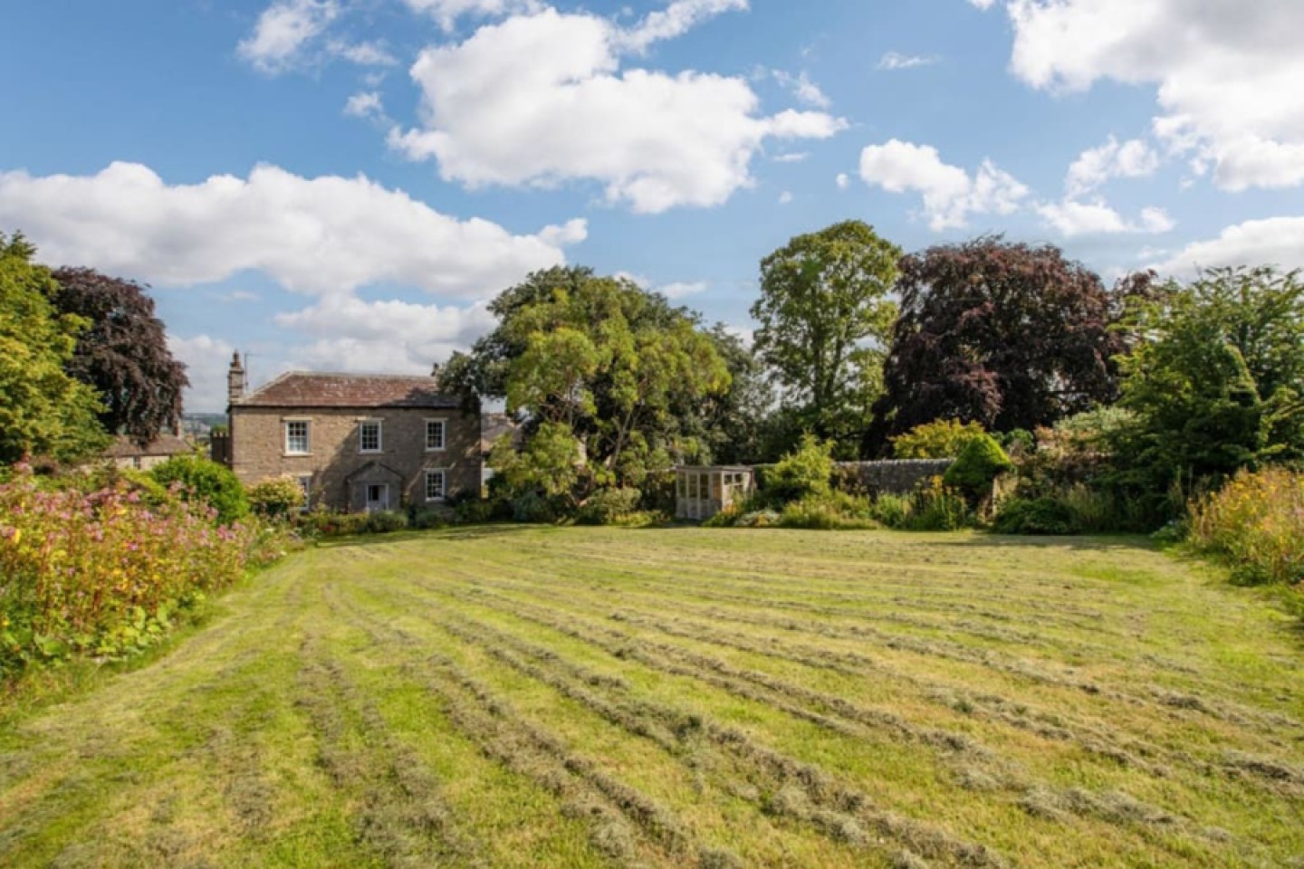 double fronted stone house, with large lawned garden