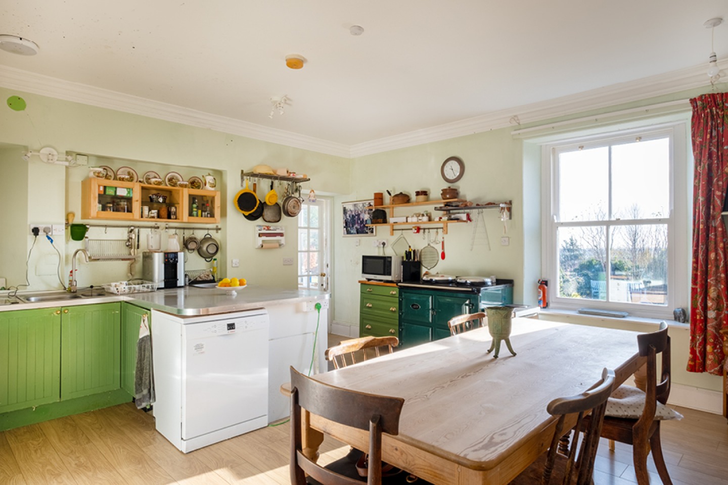 Traditional free standing kitchen with green cupboards and range cooker and large dining table