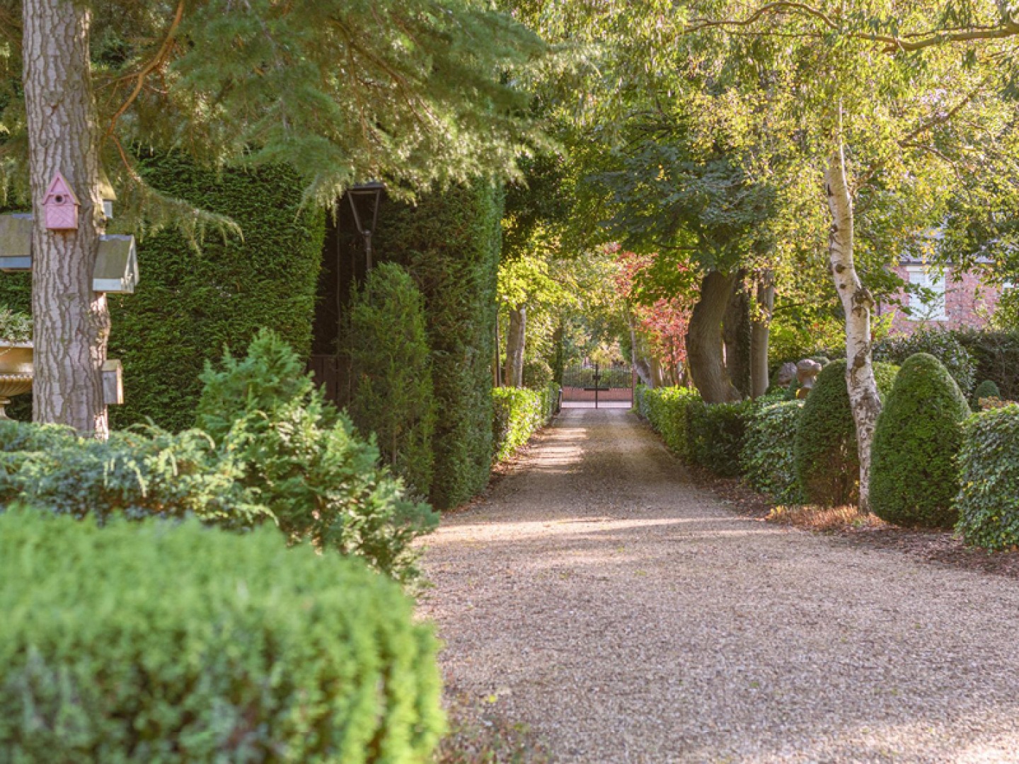 Tree lines long gravel drive way with iron gates