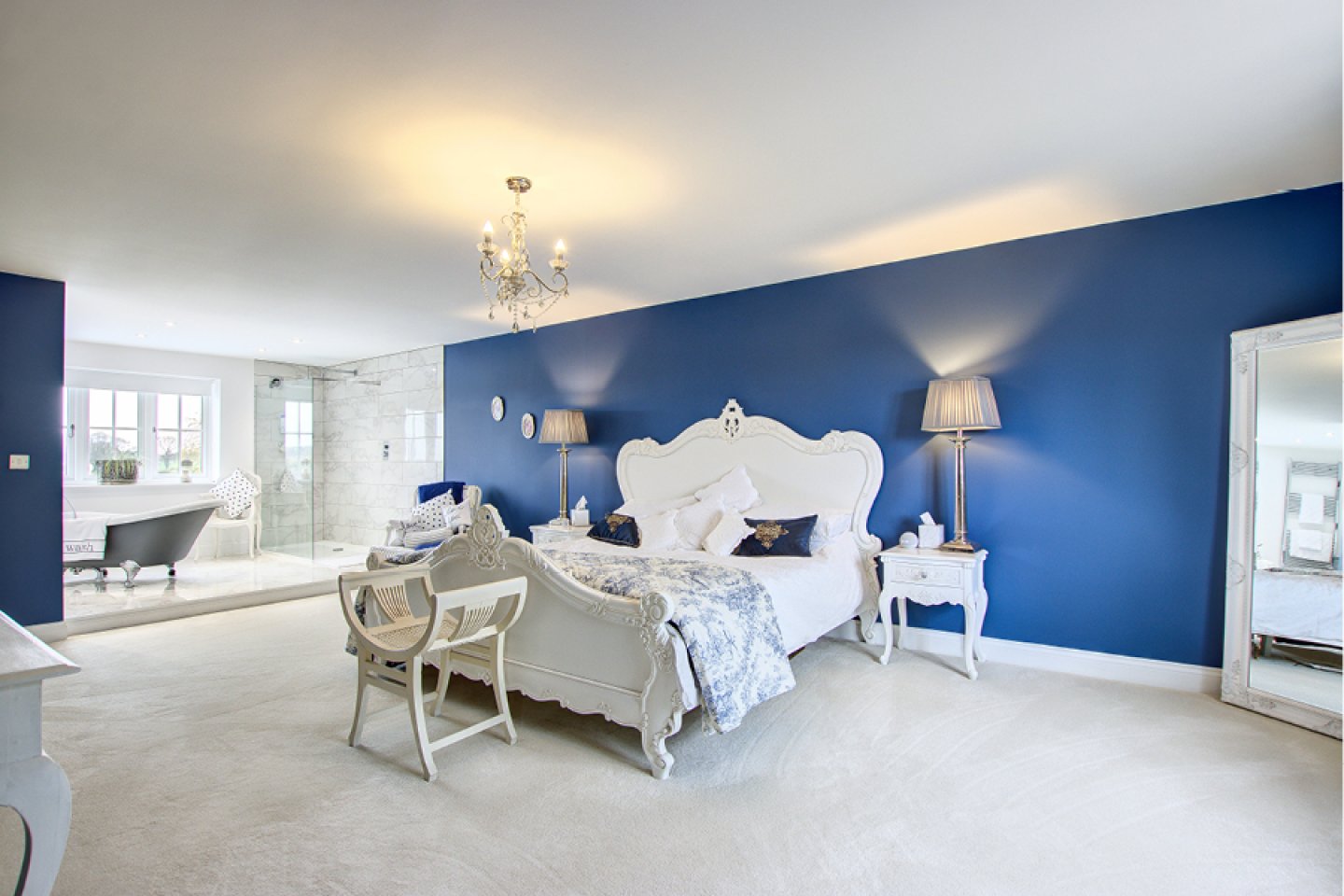 Master bedroom with open bathroom and statement blue walls