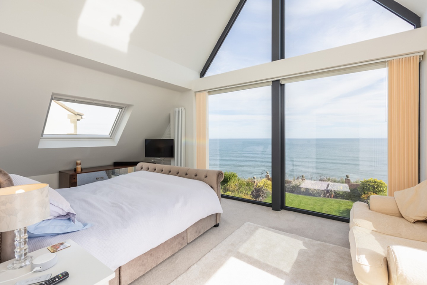 Modern bedroom with vaulted ceiling and floor to ceiling picture window