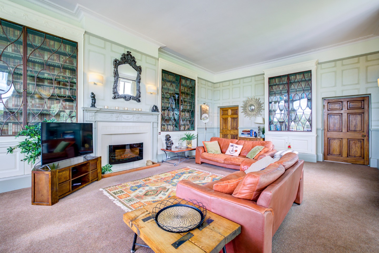 Large lounge with tall ceiling, period featured and large built-in bookcases around the walls
