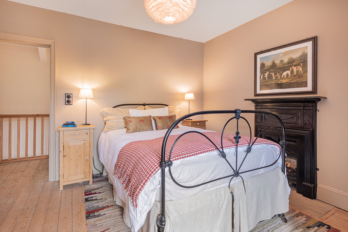 Neutral Farmhouse bedroom with black metal bed and fireplace