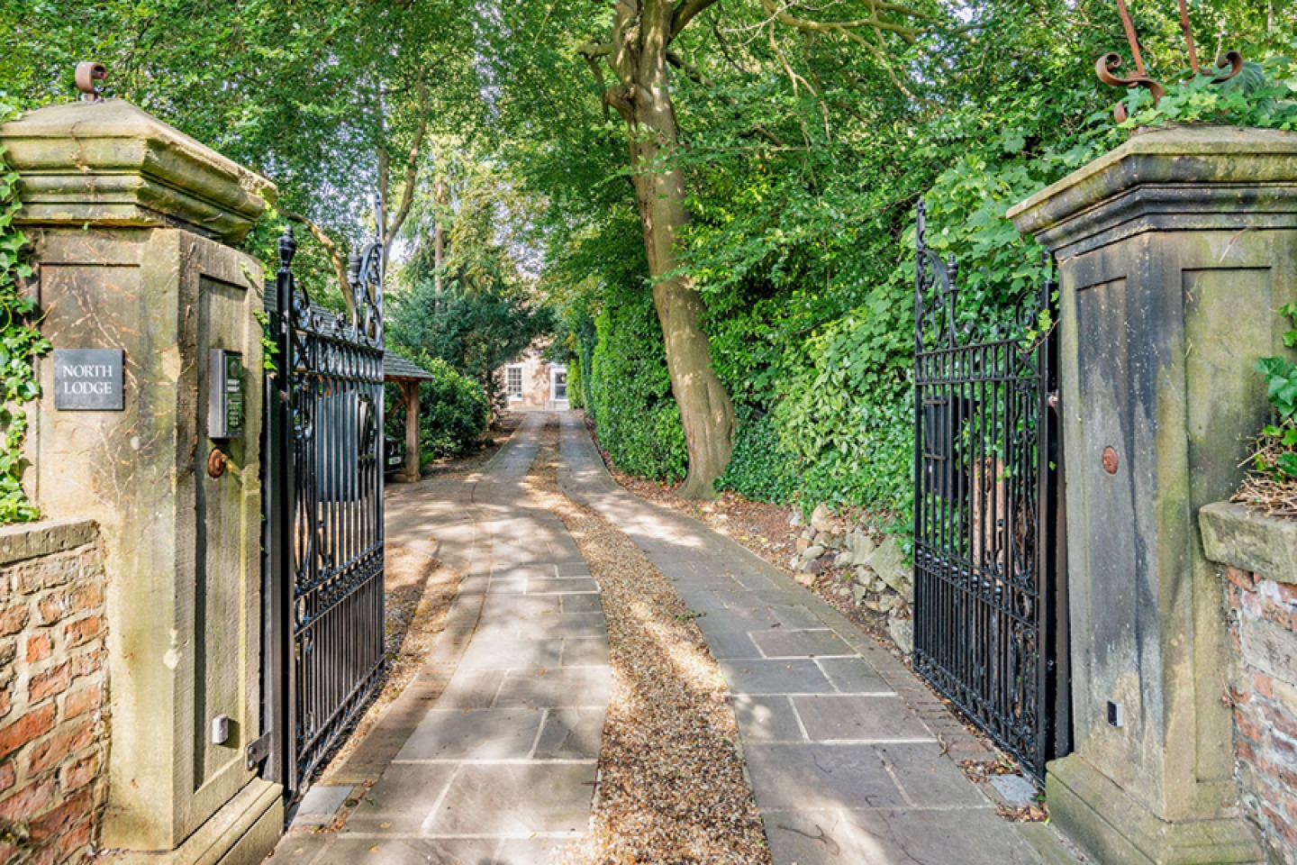 Gated tree-lined drive way with stone pillars