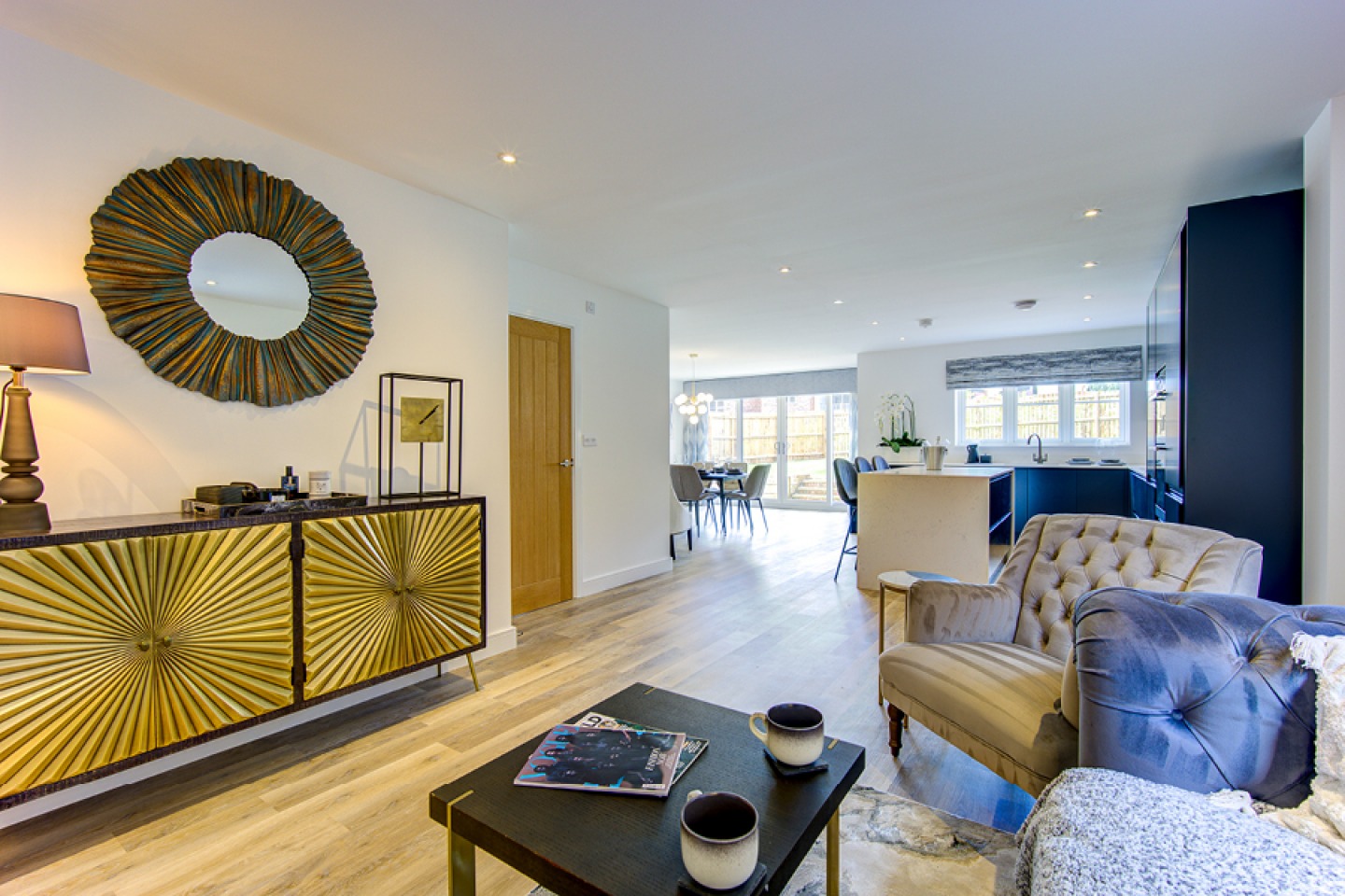 contemporary sitting area off an open plan kitchen diner with blue grey and gold furniture