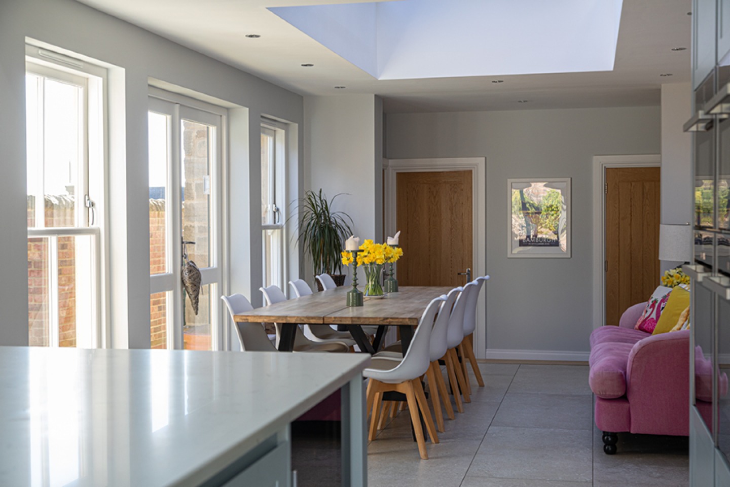 modern dining area with large table, sky lantern and pink sofa