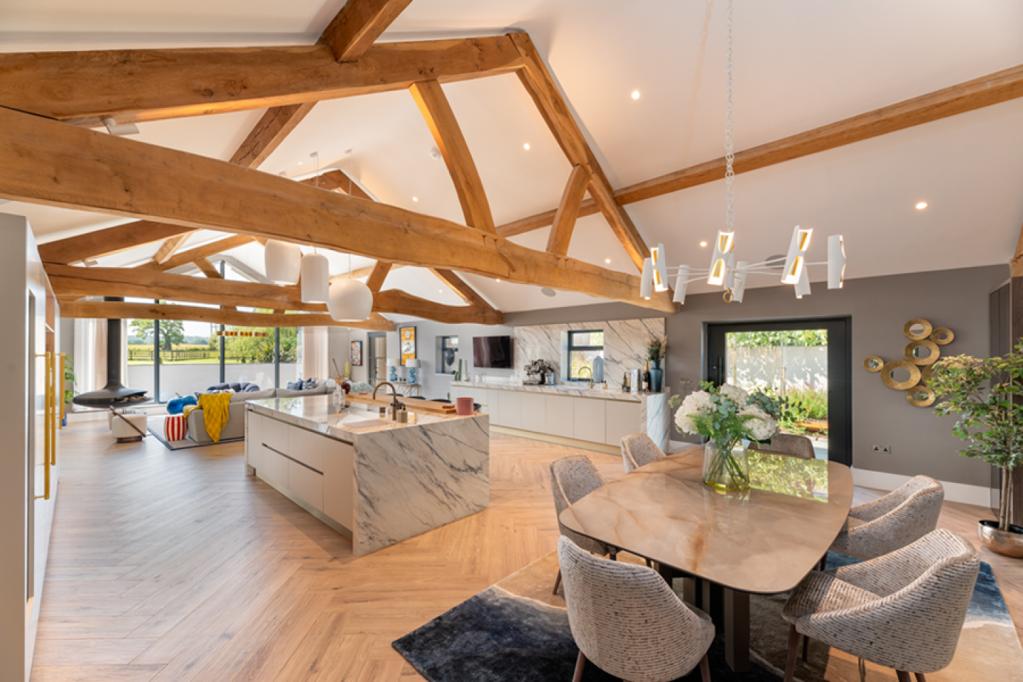 Open plan kitchen dinning lounge area with large picture windows and exposed beams