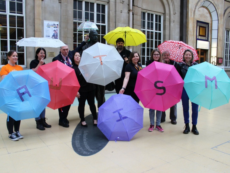 Group of people holding umbrellas that spell out autism