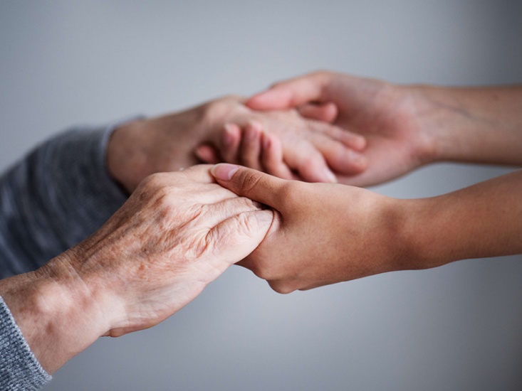 a young person holding and offer support to an older person