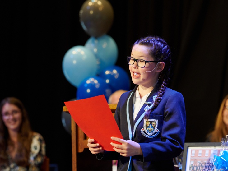 school girl holding a book on a stage