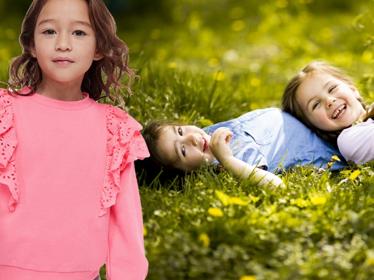 Girls in grass and wearing a pink jumper