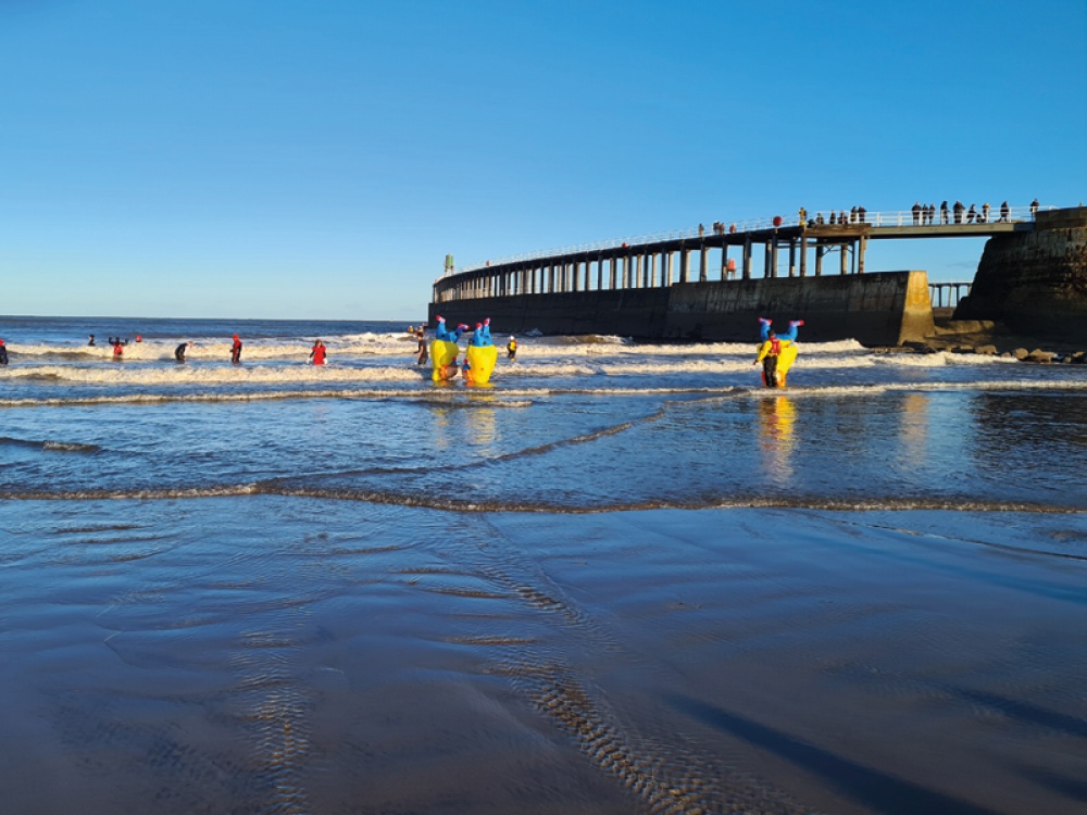 Whitby's Annual Boxing Day Dip- swimmers in fancy dress, running into the sea