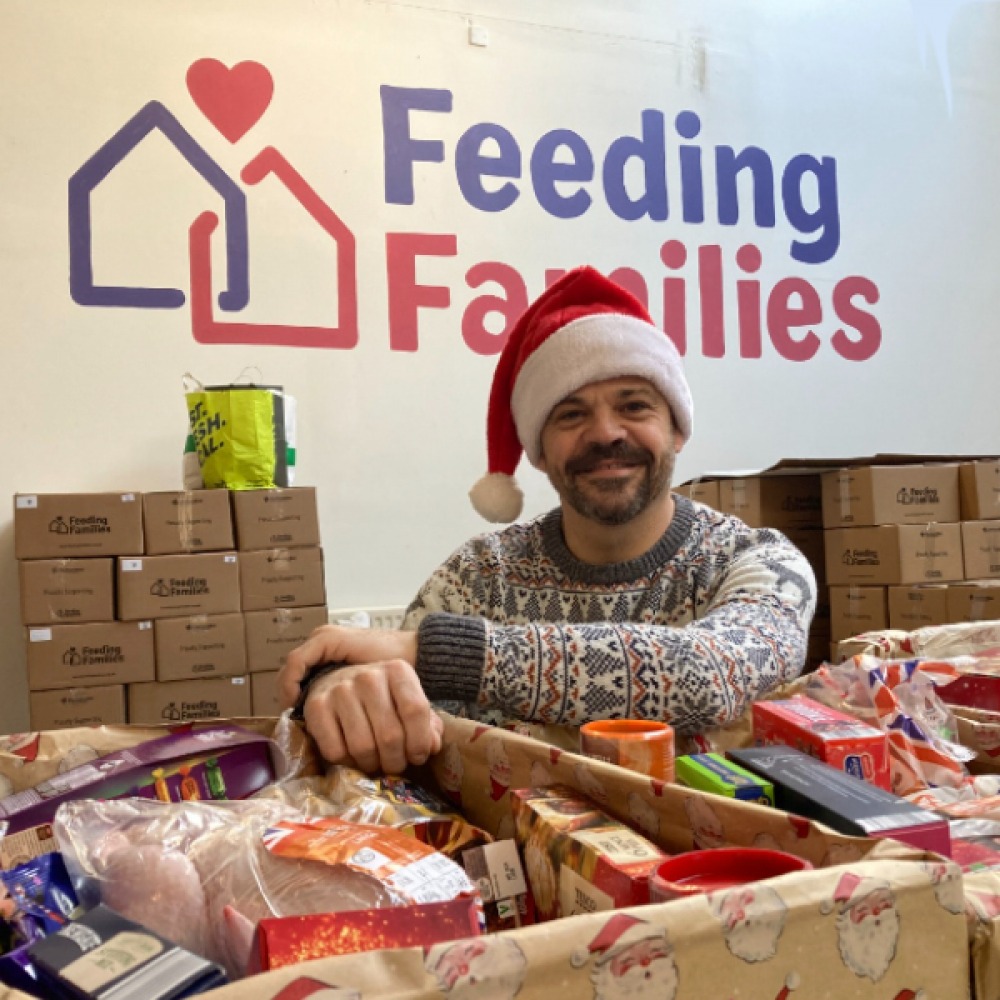 Volunteer wearing Santa hat with food donations