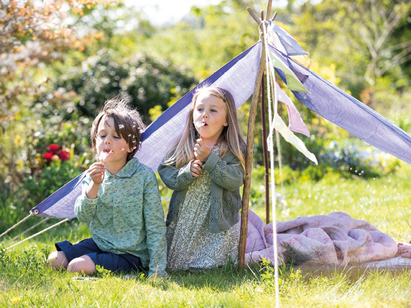 Young boy and girls playing in a purple tent den blowing bubbles