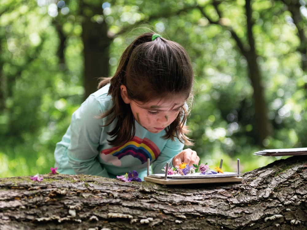 Young girl pressing flowers outside