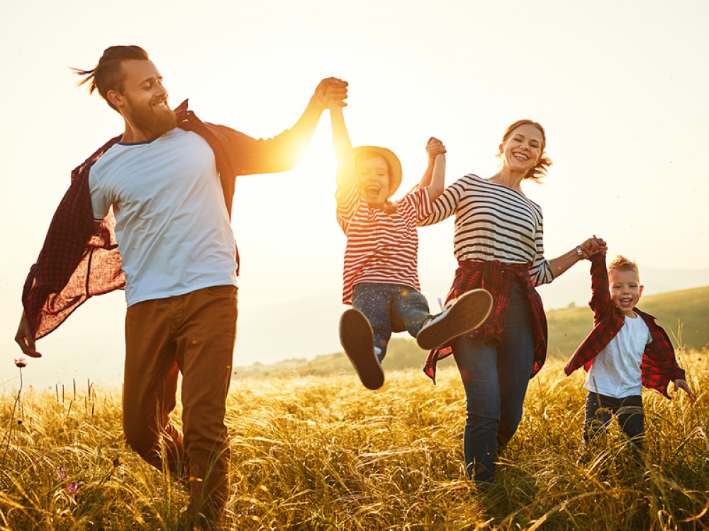 Family holding hands and lifting their daughter