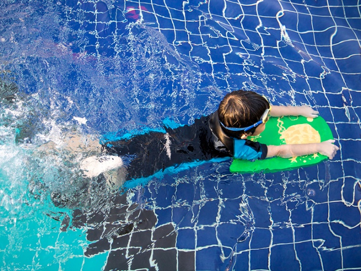Child learning to swim with float
