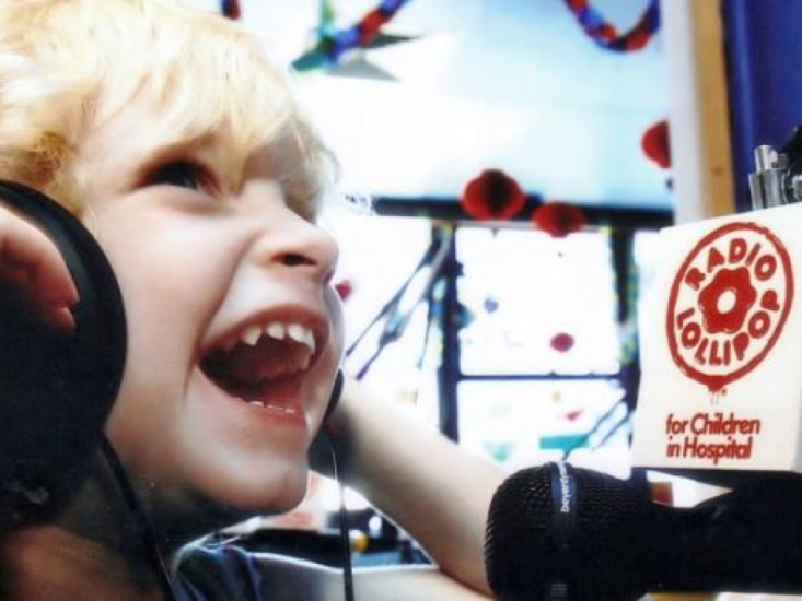 Child wearing headphones laughing in front of a Radio Lollipop Microphone