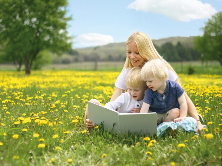 woman sitting reading in. a field with children