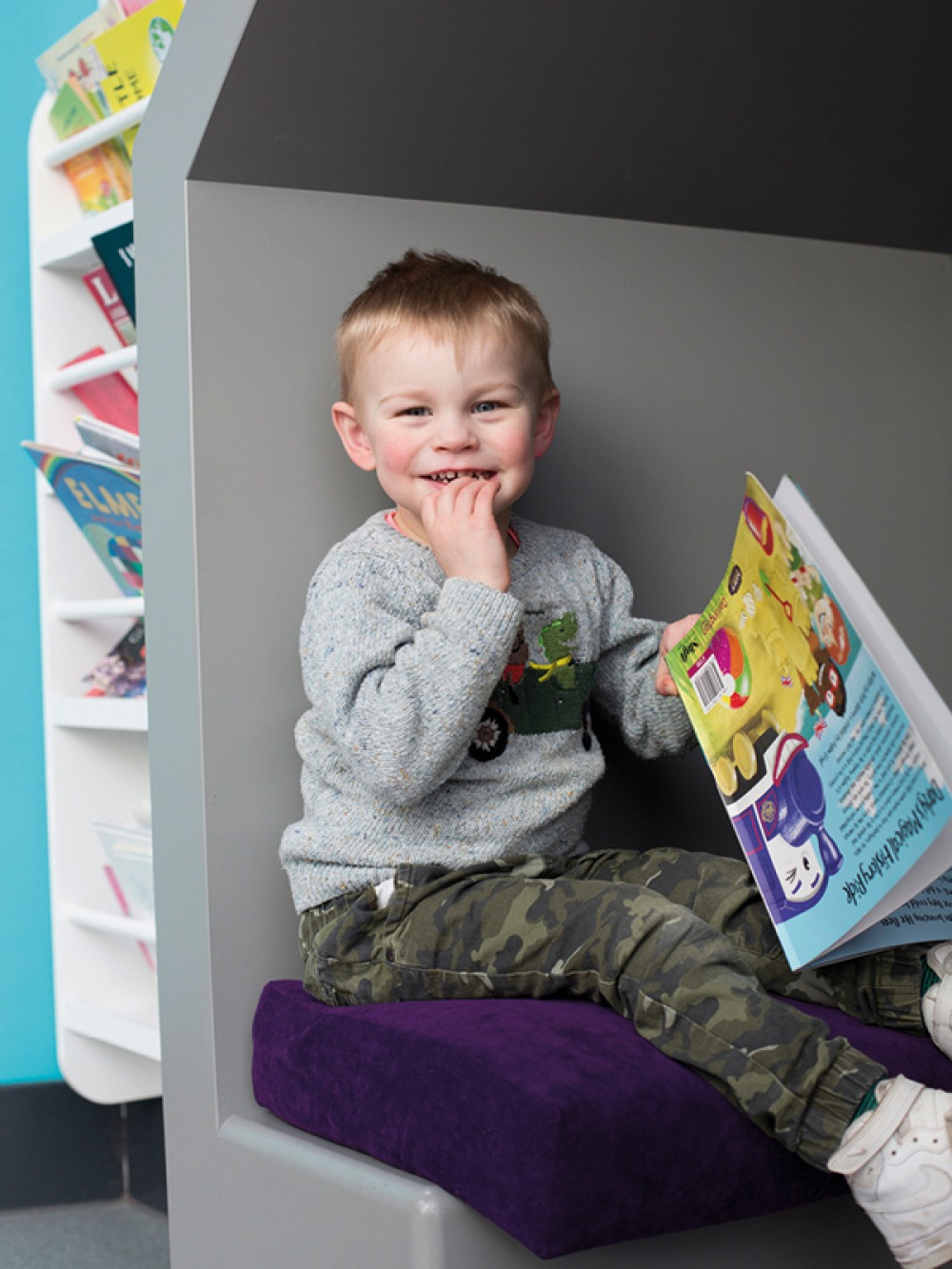 child smiling with a book in his hand