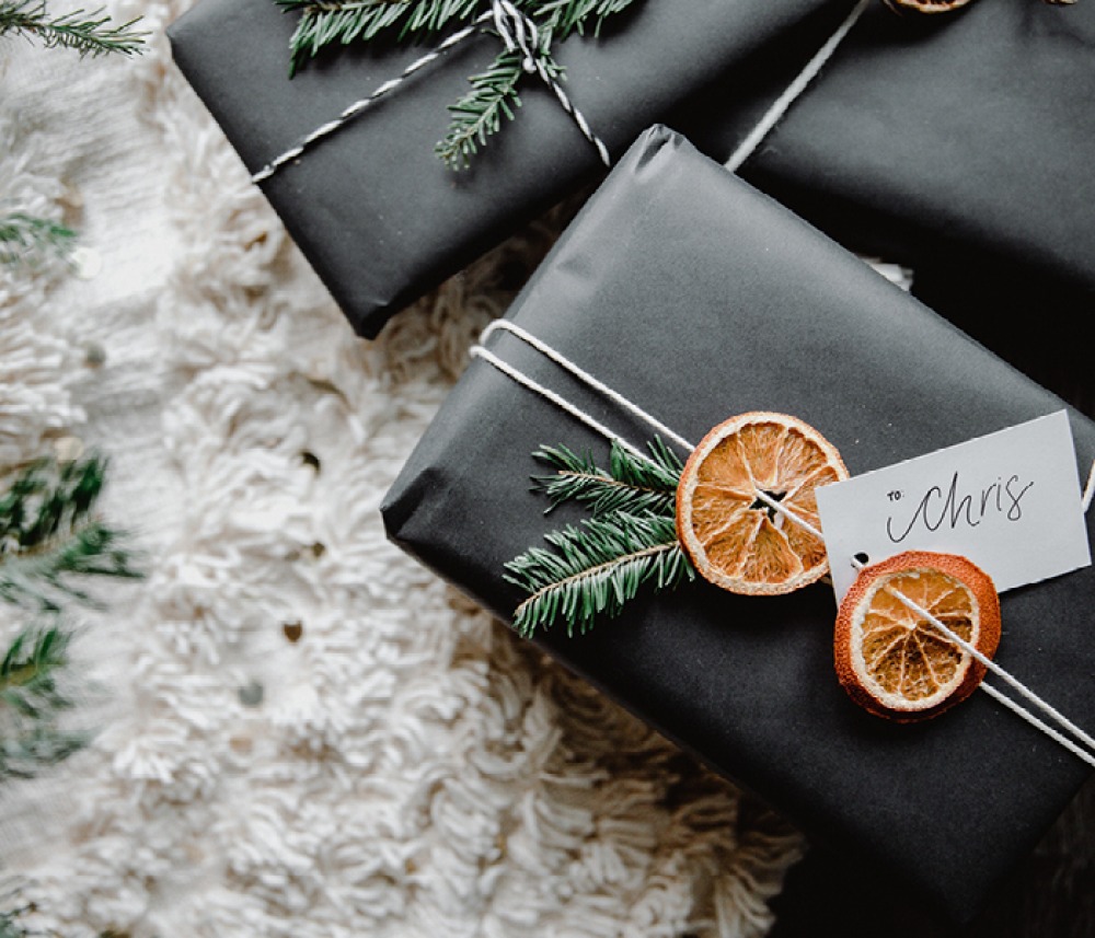 gifts wrapped in black paper, with string, firs and dried orange