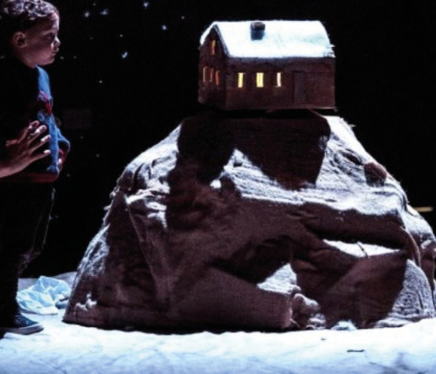 Child looking at a sculpture of a house on top of a rock