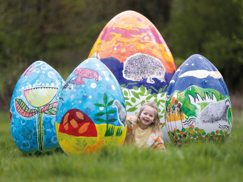 Little girl sitting amongst giant East eggs at Easter Adventure Quest at Belsay Hall, Northumberland