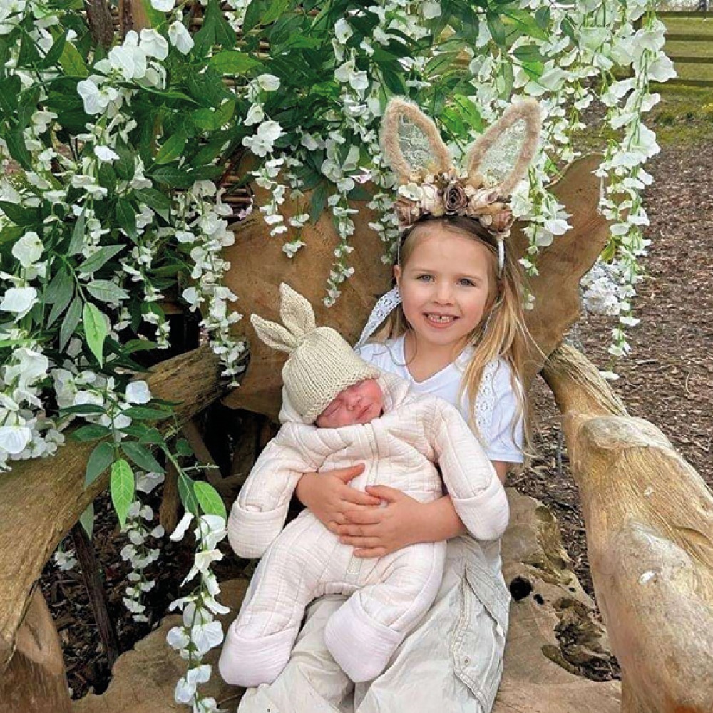 Young girl with a baby on her lap both wearing bunny ears