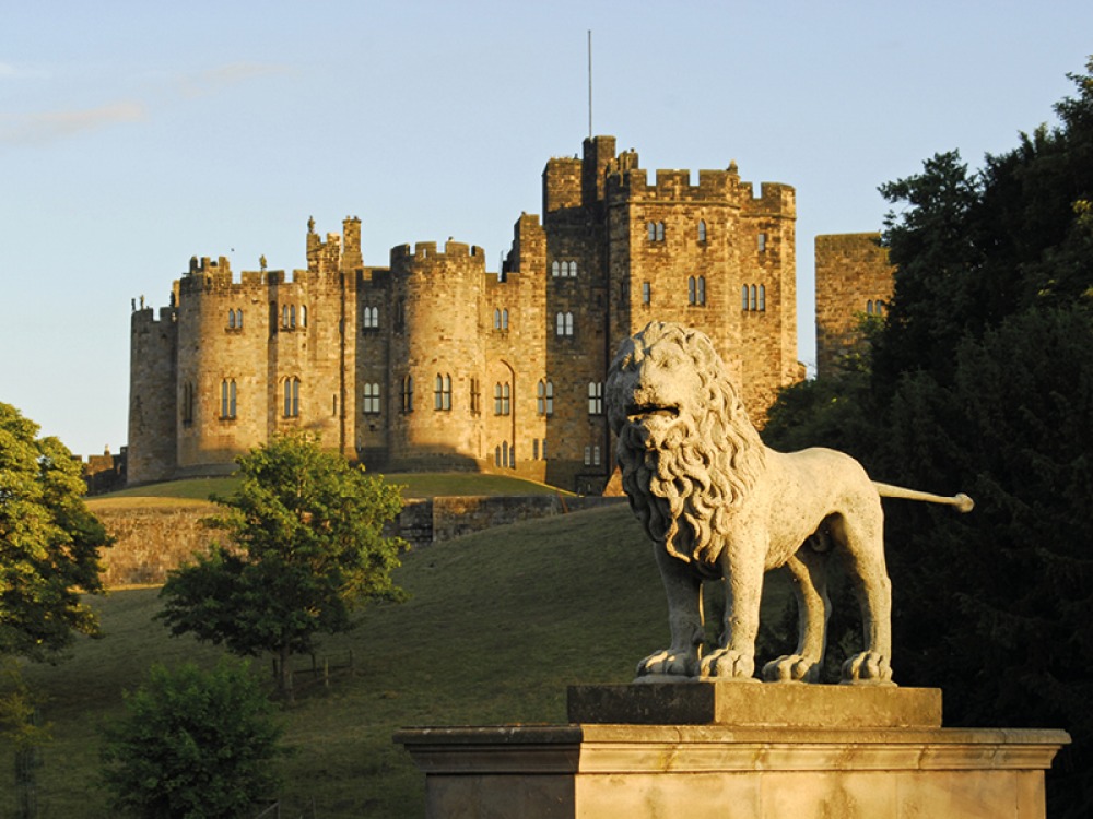 Large stone lion statute in the foreground of Alnwick Castle
