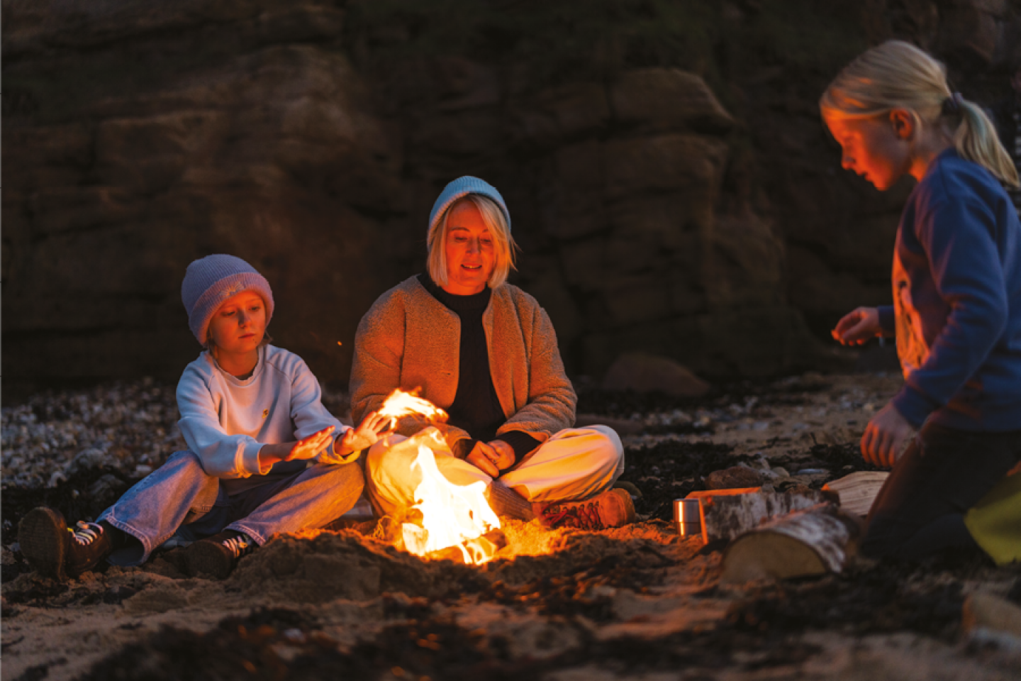 Mother and two daughters sitting around a camp fire