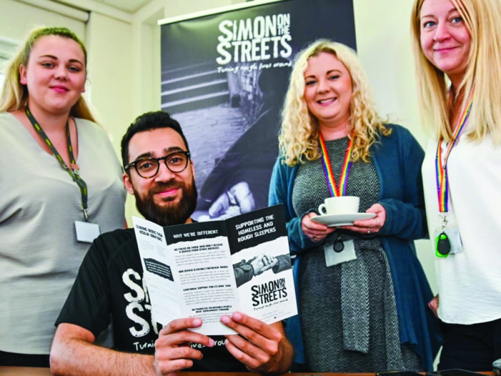 4 people reading a Simon on the streets leaflet