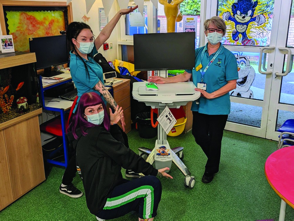 3 woman standing around a computer game station for hospitals