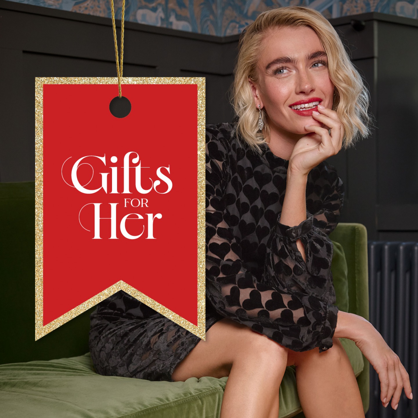 woman wearing a black party dress sitting on a couch resting her chin in her hand