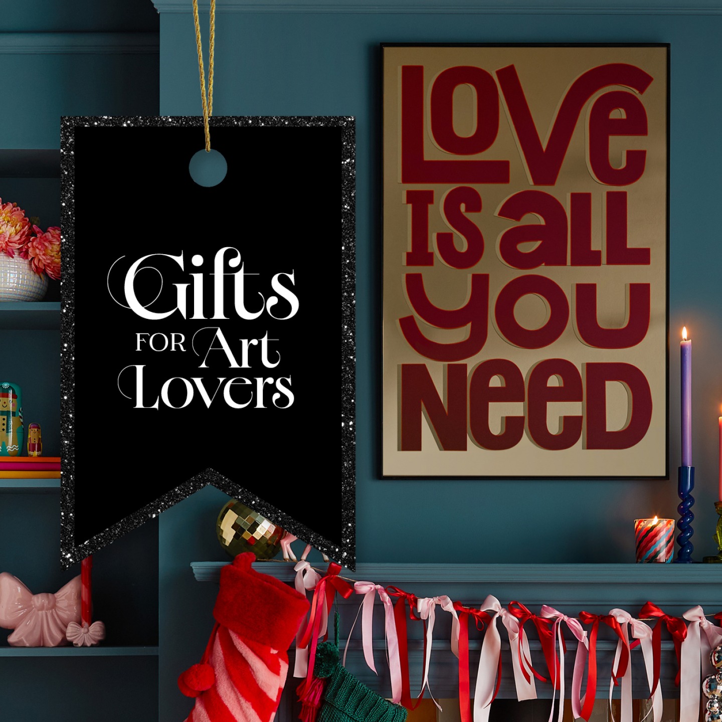 'Love is all you need' artwork hung on chimney breast with christmas decorations around the fireplace