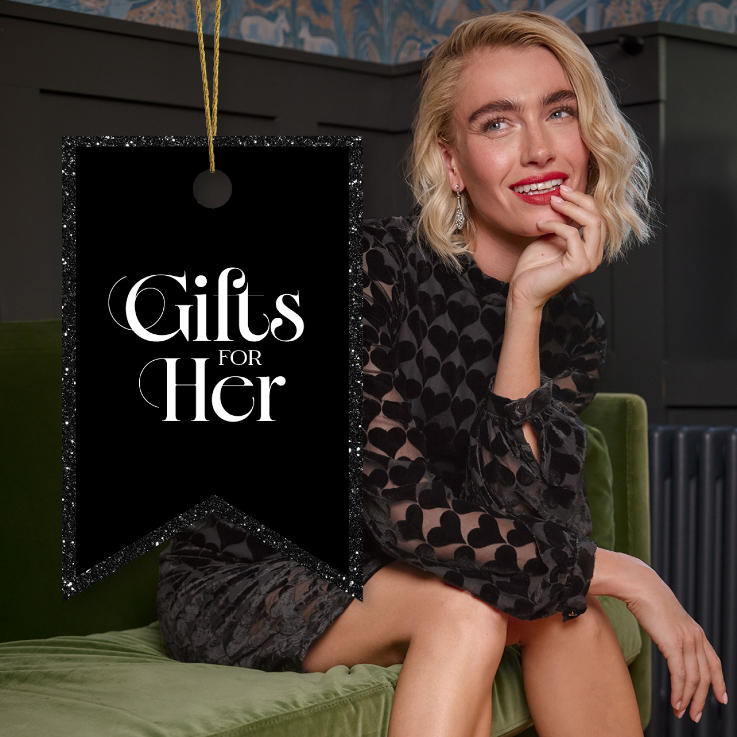 woman wearing a black party dress sitting on a couch resting her chin in her hand