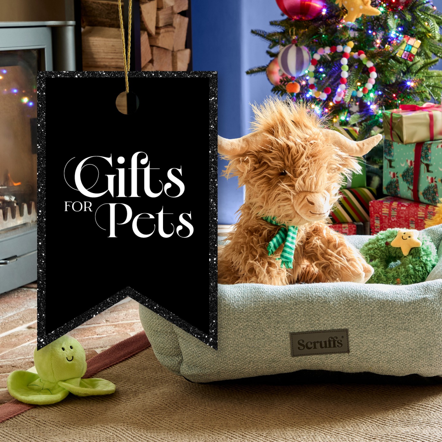 Highland cow teddy in a dogs bed with Christmas tree in background