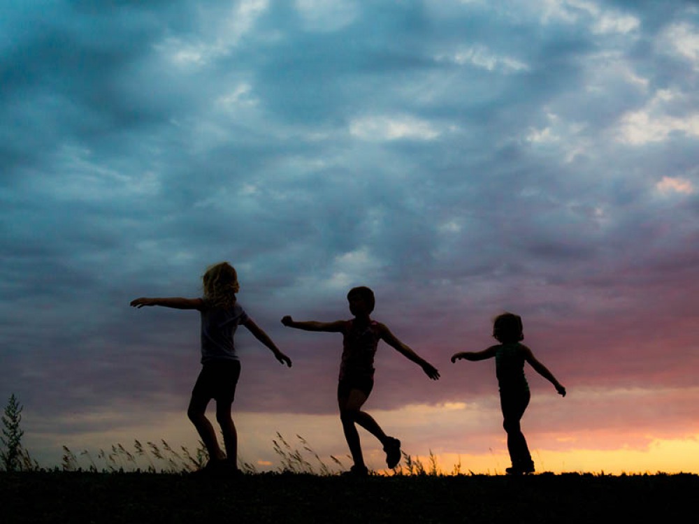 silhouettes of children walking in a line playfully