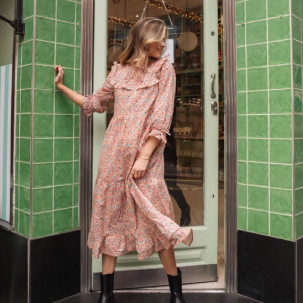 woman in doorway wearing pink midi dress and black boots