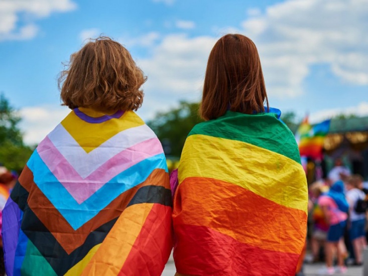 two young people wearing pride flags around their back