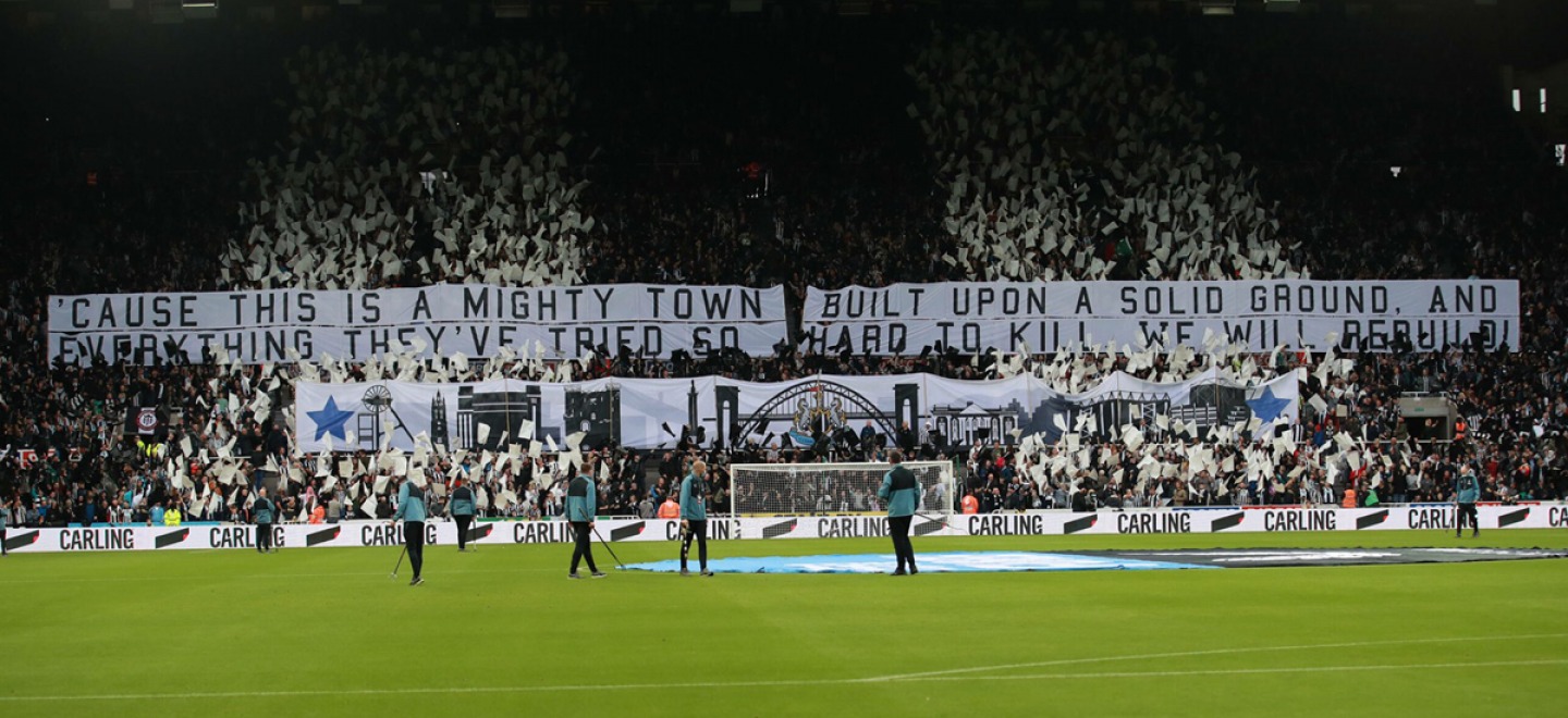 Football supporters holding black and white flags during a pitch inspection