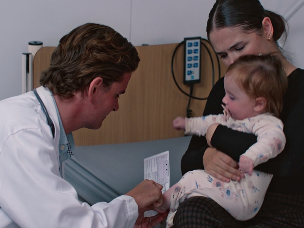 Doctor doing a blood spot test on a baby in mothers arms