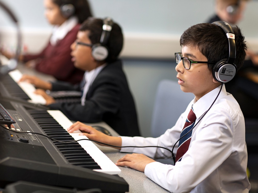Students wearing headphones playing keyboard