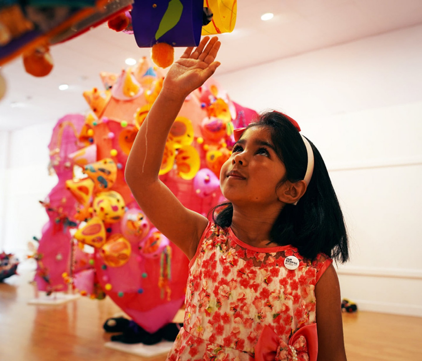 young girl holding her hand up to a piece of hanging art