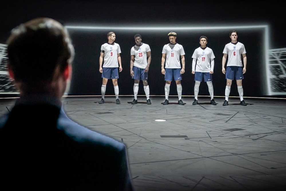 Footballers lined up in England shirts in front of a goal in Dear England