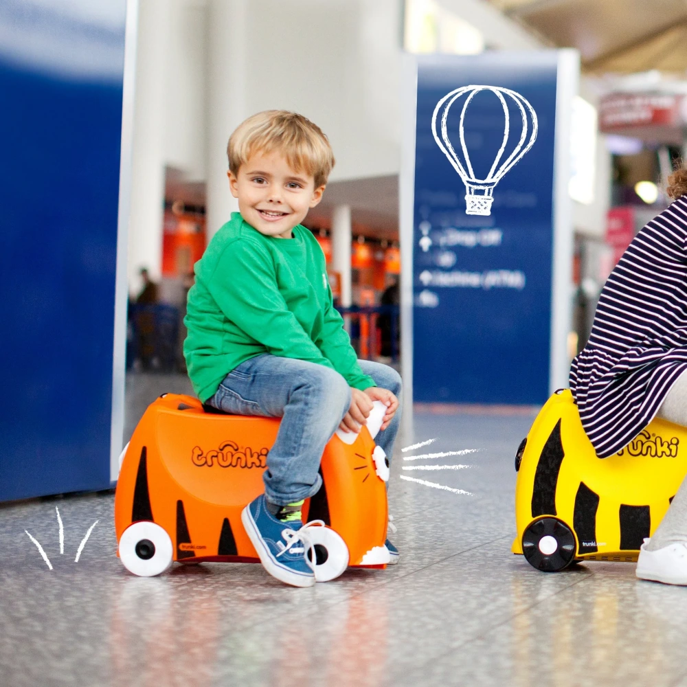 child riding along in airport on a Trunki Case