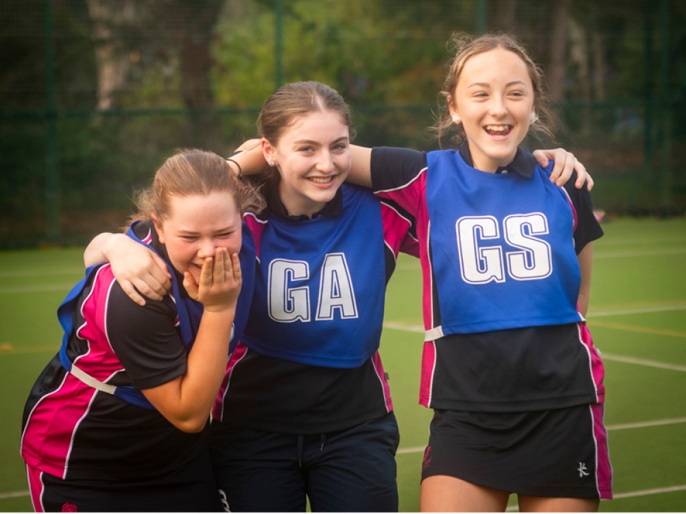 3 Girls in netball bibs laughing