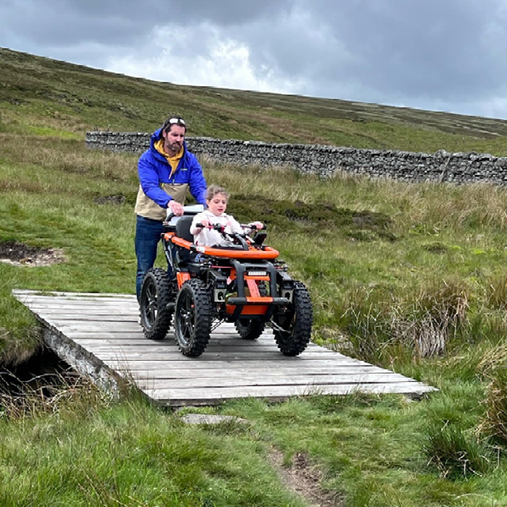 Young girl in wheelchair pushed by her dad in the yorkshire dales